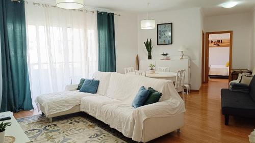 a living room with a white couch with blue pillows at Refúgio Garajau Madeira in Caniço