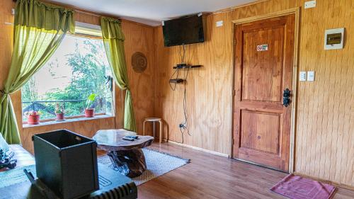 - un salon avec une télévision et une porte dans l'établissement Cabañas Estrella del Sur, à Puerto Varas