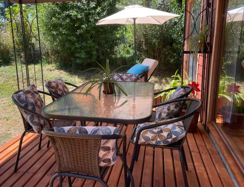 a table and chairs on a porch with an umbrella at Comodidad y hermosa Vista Volcán in Melipeuco