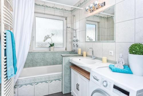 a white bathroom with a tub and a sink at Staufenhirsch Apartment in Oberstaufen