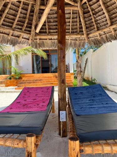 dos camas sentadas bajo un techo de paja en Bwereu Sunset Villas 