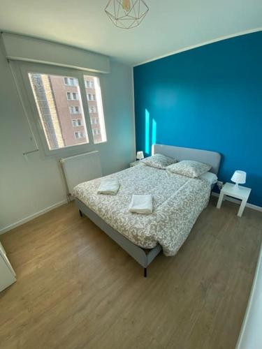 een slaapkamer met een bed en een blauwe muur bij Splendide 70m2 Balcon + Parking in Clermont-Ferrand