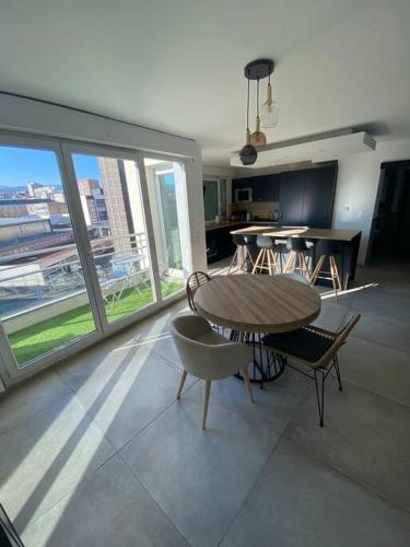 - un salon avec une table, des chaises et une grande fenêtre dans l'établissement Splendide 70m2 Balcon + Parking, à Clermont-Ferrand