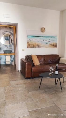 a living room with a brown leather couch and a table at Villa Oasi dune e mare in Campobello di Mazara