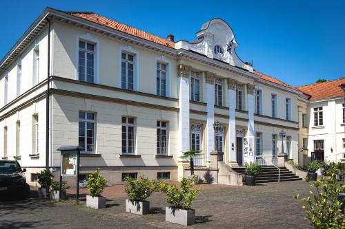 een groot wit gebouw met bomen ervoor bij Schlosshotel Westerholt in Herten