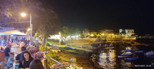 a group of people sitting at tables by a river at night at Villa Oasi dune e mare in Campobello di Mazara