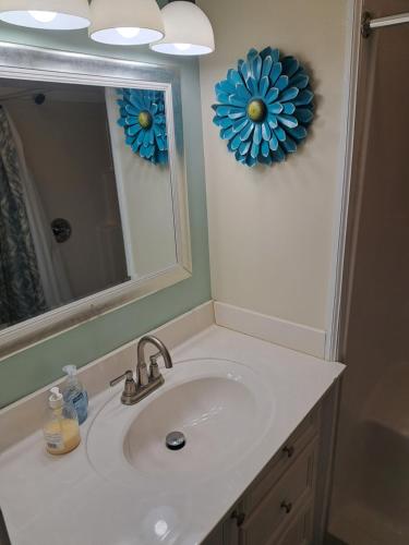 lavabo en el baño con espejo y una flor azul en la pared en Piano Room Studio with full kitchen and no fees en Florence