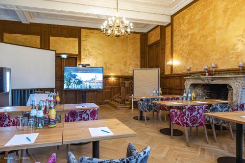 a room with tables and chairs and a projection screen at Schlosshotel Westerholt in Herten