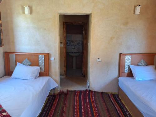 twee bedden in een kamer met een deuropening bij Mezorin Camp in Siwa