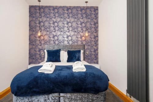 a bedroom with a blue bed with two towels on it at The Retreat At The Lawrence Apartments in York