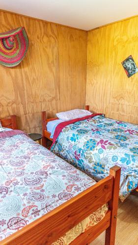 two beds in a room with wooden walls at Cabañas Estrella del Sur in Puerto Varas