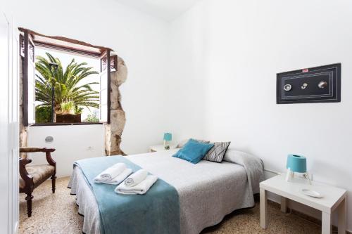 a white bedroom with a bed and a window at El Hostal del Cubo in San Juan de la Rambla