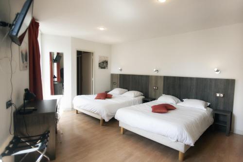 um quarto com 2 camas com lençóis brancos e almofadas vermelhas em Le Victor Hugo - Hôtel et Restaurant - Logis Hôtels em Saint-Céré