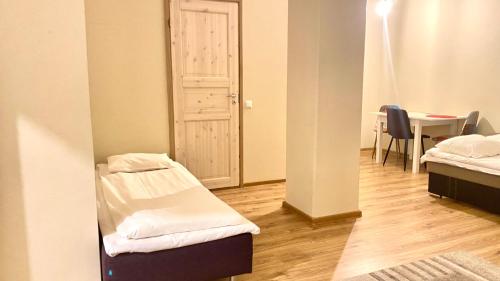 a room with two beds and a table and a door at Kastanimaja Apartments in Tartu