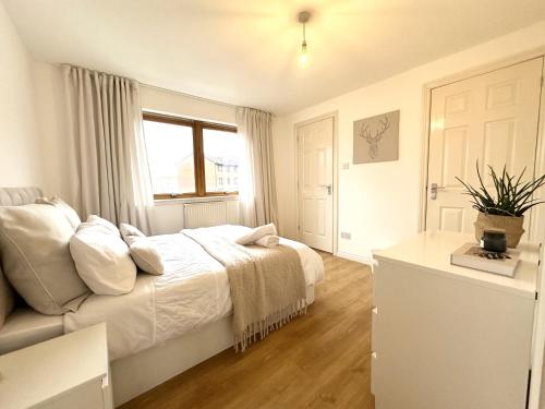 een witte slaapkamer met een bed en een raam bij Private room with en-suite and parking in shared flat in Glasgow