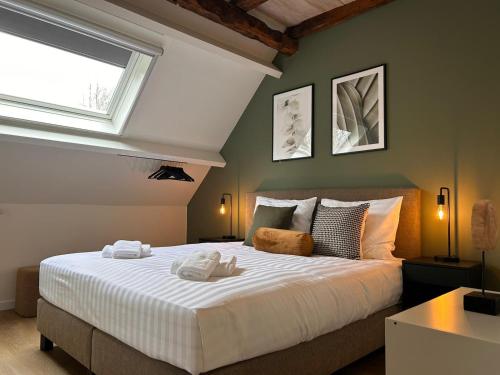 a bedroom with a large white bed with a window at Hotel De Hoogmolen in Oudsbergen 