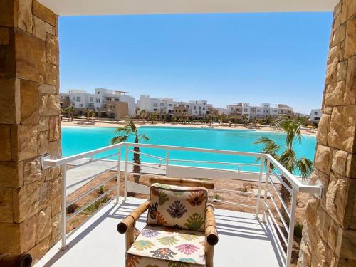 une chaise sur un balcon avec vue sur la piscine dans l'établissement Swan Lake Crystal Lagoon View Chalet, à Hurghada