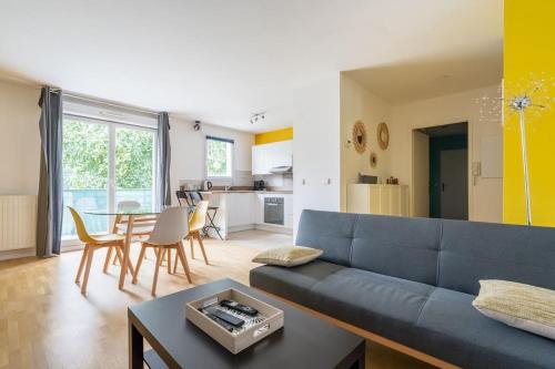 a living room with a blue couch and a table at Élégant Appartement Familial Disneyland & Gare RER in Bussy-Saint-Georges