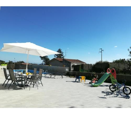 um parque infantil com um escorrega e cadeiras e um guarda-sol em Etna Sicily vulcano house em Fleri