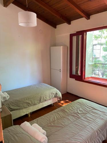 um quarto com 2 camas, um frigorífico e uma janela em La casona de Palermo Hostel Boutique em Buenos Aires