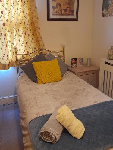 a bed with a yellow pillow and a towel on it at Shakespeare in Measham