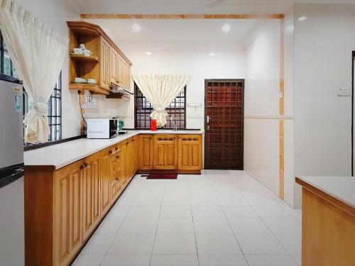 a kitchen with wooden cabinets and a white tile floor at Ipoh Sunway 20Pax 5 mins Lost World Holiday Home by City Home Empire in Tambun