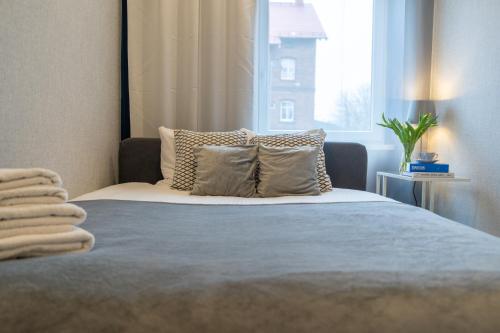 a bedroom with a bed with pillows and a window at Apartament BIANCO w sercu Śląska in Ruda Śląska
