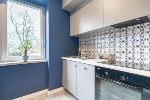 cocina con paredes azules y ventana en Apartament BIANCO w sercu Śląska en Ruda Śląska