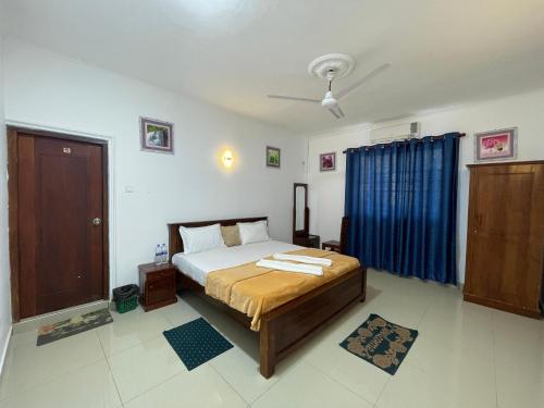 VIP Hotel And Villa في بيرووالا: غرفة نوم بسرير وستارة زرقاء