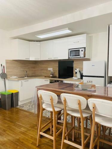 une cuisine avec une table en bois et des armoires blanches dans l'établissement Le logis de la lanterne*Centre Historique de Sarlat, à Sarlat-la-Canéda