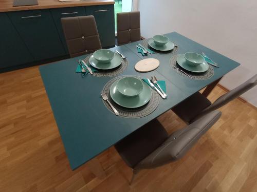 una mesa azul con platos verdes y utensilios. en DOLCE VITA CASA, en Pápa