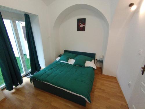 a bedroom with a green bed in a room with windows at DOLCE VITA CASA in Pápa