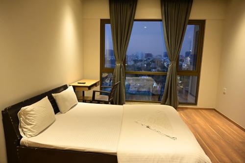 a hotel room with a bed and a large window at Niva Stays Riverside 1 in Kharadi