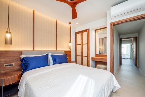 a bedroom with a large white bed with blue pillows at Porto Perla in Kos Town
