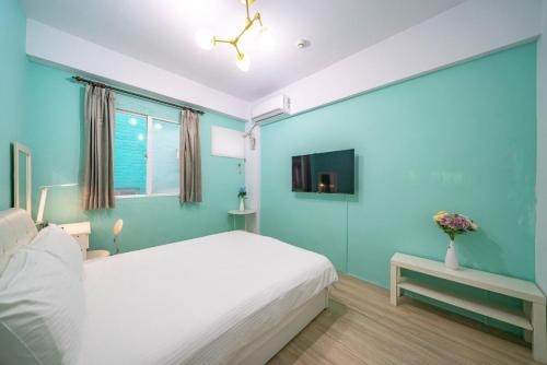 a bedroom with a white bed and a blue wall at GREEN INN in Wujie