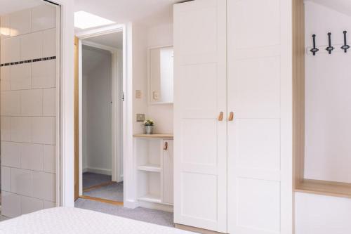a bathroom with white cabinets and a mirror at Contemporary mid-terrace cottage in Priors Marston
