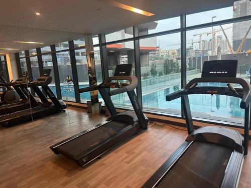 een fitnessruimte met verschillende loopbanden in een gebouw bij Autumn Falls, 2 Bedroom full service equipped appartement in Dubai