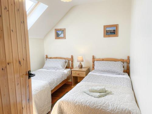 two twin beds in a room with a window at Inish Holiday Cottage in Kilmore Quay