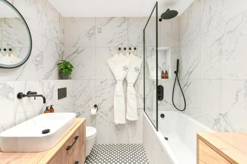 a white bathroom with a shower and a sink at Buckingham and Lloyds - South Kensington in London