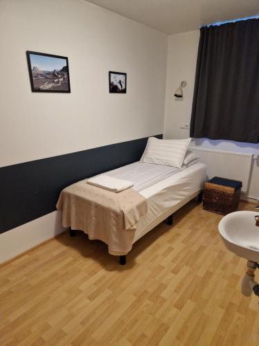 um pequeno quarto com uma cama e um lavatório em Gauksmýri guesthouse em Hvammstangi