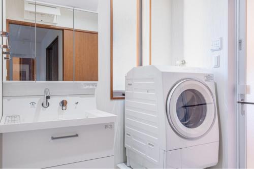 a white bathroom with a washing machine and a sink at Residencial Voyan 南砂町 in Tokyo