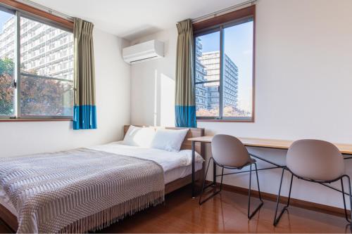 a bedroom with a bed and two chairs and windows at Residencial Voyan 南砂町 in Tokyo