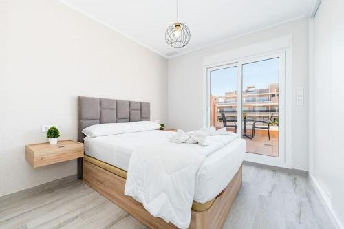 a white bedroom with a large bed and a window at Palace Torre de la Horadada in Torre de la Horadada