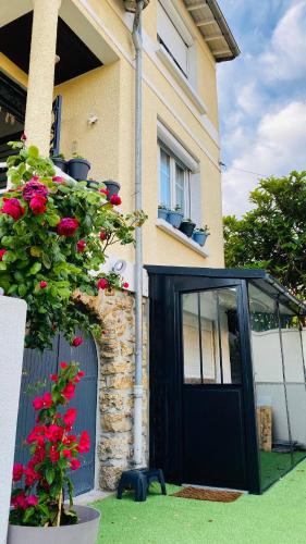uma casa com uma porta preta e algumas flores em Charmant logement parking gratuit, gare proximité em Sevran