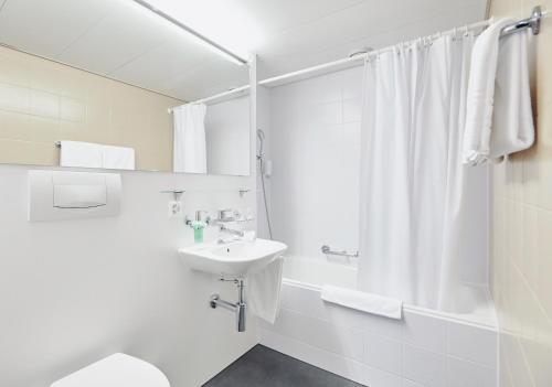 La salle de bains blanche est pourvue d'un lavabo et d'une douche. dans l'établissement Hotel Schiff am Rhein, à Rheinfelden