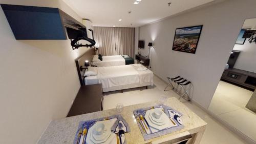 a hotel room with a bed and a table with plates on it at Lindos Flats Studios no Qualité in João Pessoa