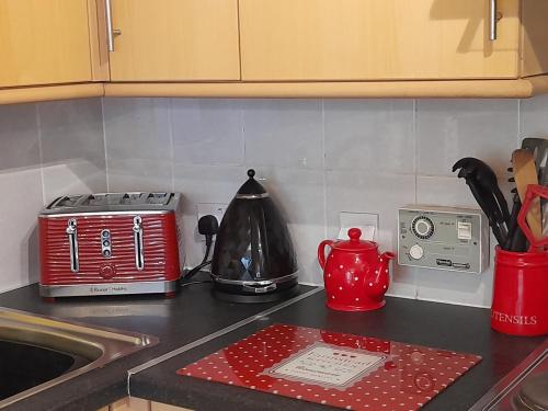 a kitchen counter with a red toaster and a sink at Shakespeare in Measham