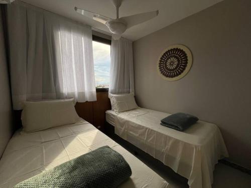 two beds in a room with a window at Mar & Descanso Itaparica in Vila Velha