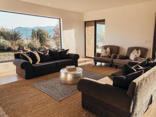 a living room with two couches and a large window at Sensiri Myst Country House in Dullstroom