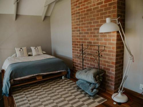 a bedroom with a bed next to a brick wall at Sensiri Myst Country House in Dullstroom